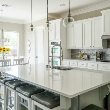 Spacious modern kitchen with white cabinets and island in natural light.