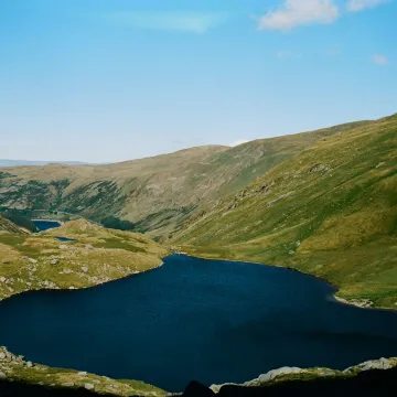 Aerial view of a tranquil lake surrounded by rolling hills in England's Lake District.