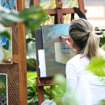 A woman enjoys painting in a lush outdoor garden, 
