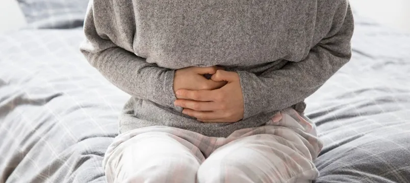 Sick woman with hands on stomach suffering from