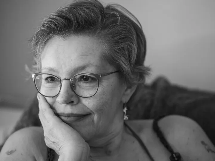 Black and white portrait of a thoughtful senior woman with glasses, reflecting indoors.
