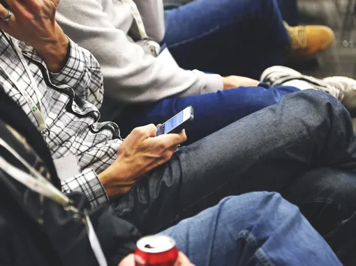 People sitting at a conference casually checking