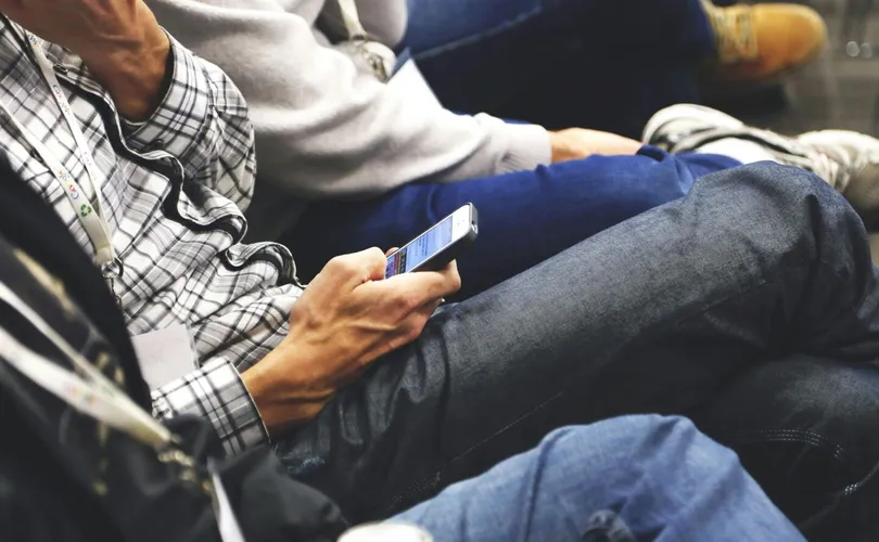 People sitting at a conference casually checking