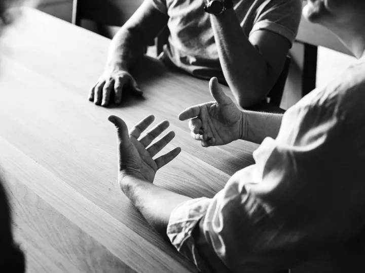 Black and white view of hands gesturing during a discussion at a table