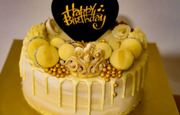 Stylish yellow birthday cake adorned with macarons and golde