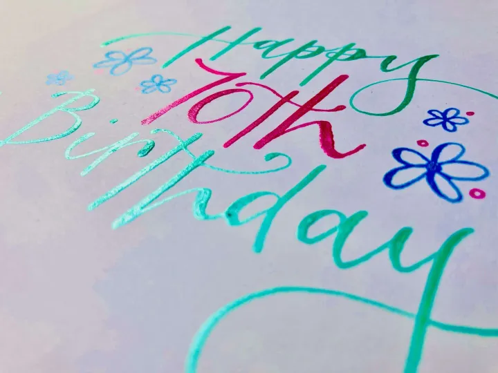 Turquoise and pink brush lettering with hand drawn flowers on a birthday card