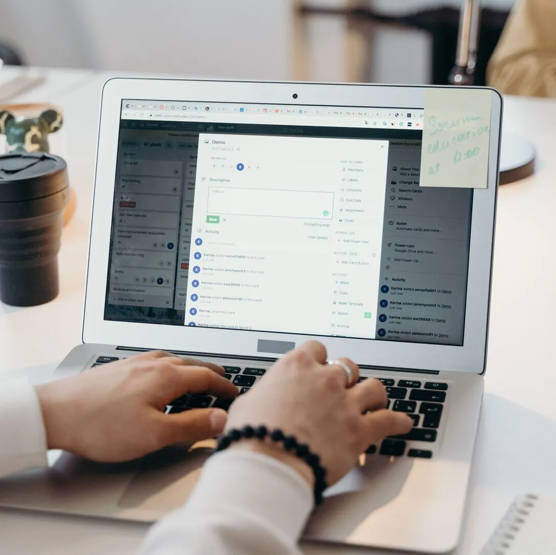 Hands typing an email at a laptop on a bright desk