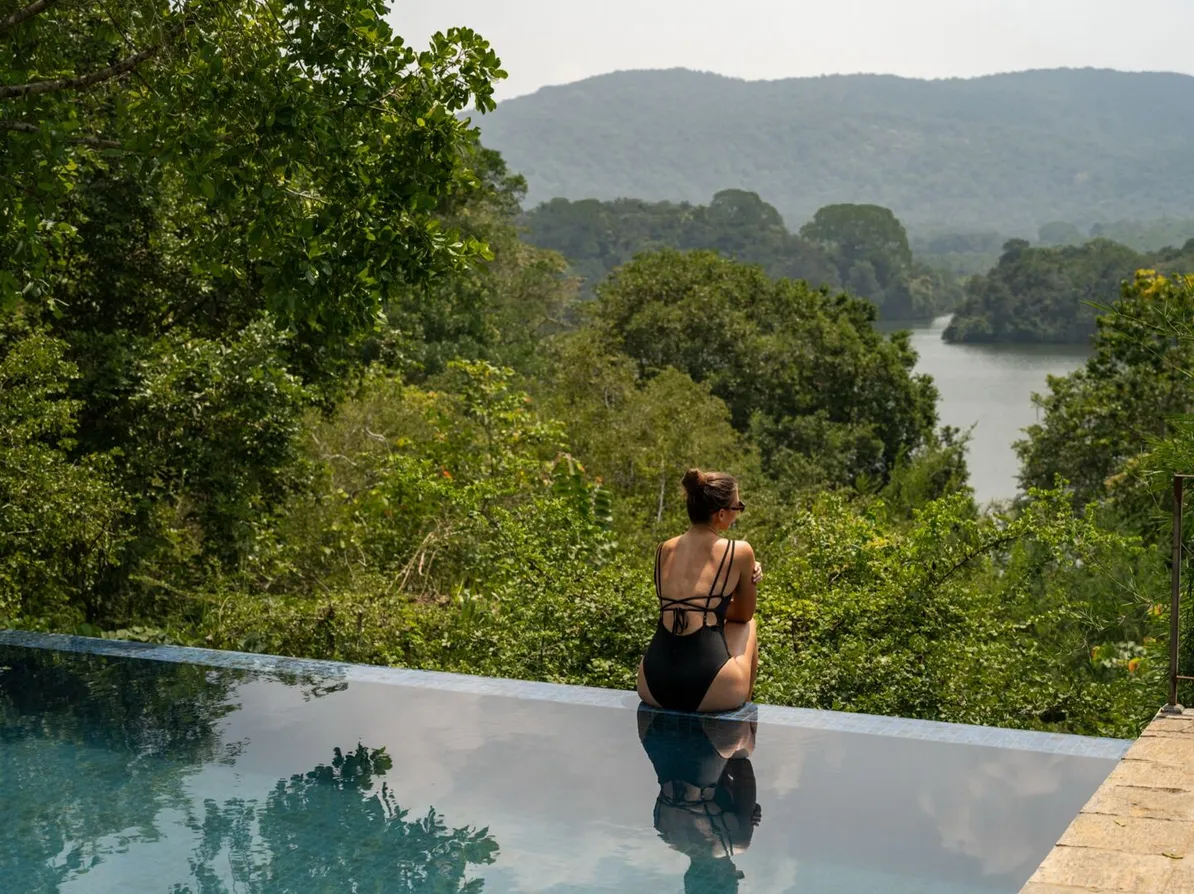 A guest standing in the infinity pool looking towards Wewela Lake at Peacock Hill Sigiriya