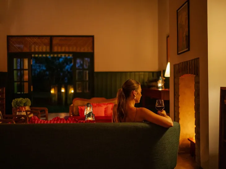 A guest with a drink beside the lounge fireplace at Peacock Hill Sigiriya