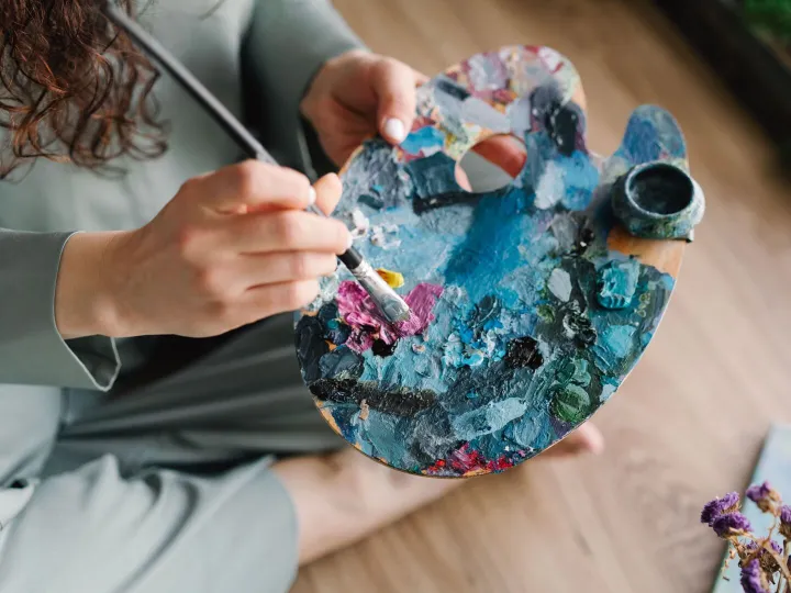 Close-up of hands painting on a colorful palette