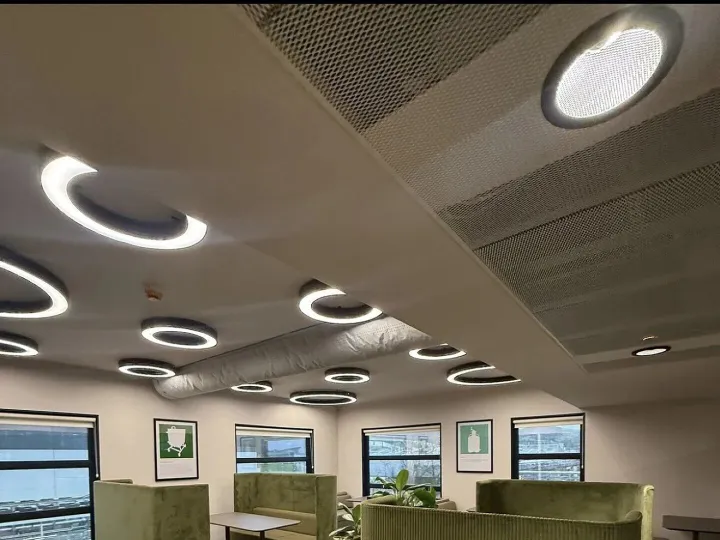 Breakout area with olive green high-backed booth seating, ring ceiling lights and framed prints