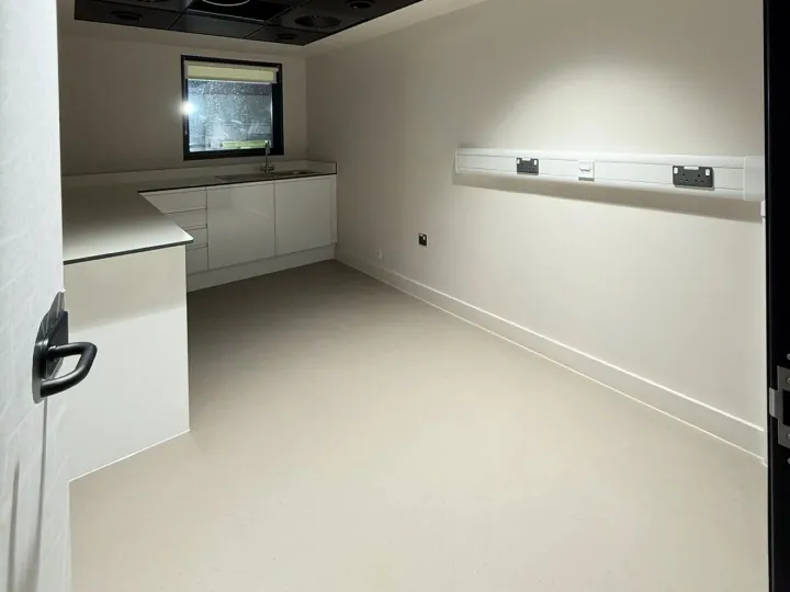 White utility room with fitted base units, a sink and wall trunking with sockets