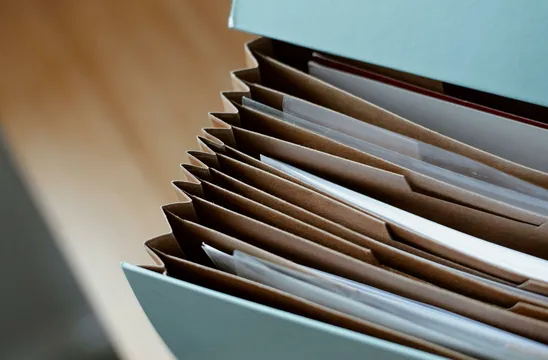 High angle of opened briefcase for documents with papers accosted in order placed on wooden table