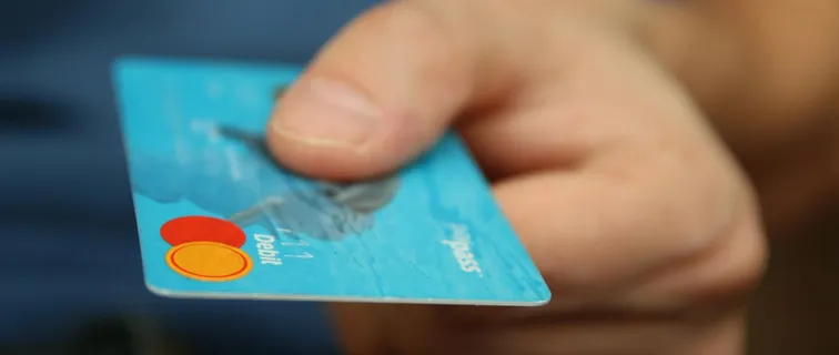 A close-up shot of a hand offering a blue debit