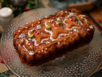 Delicious gingerbread cake topped with festive icing and sprinkles on a glass platter, perfect for holiday celebrations.