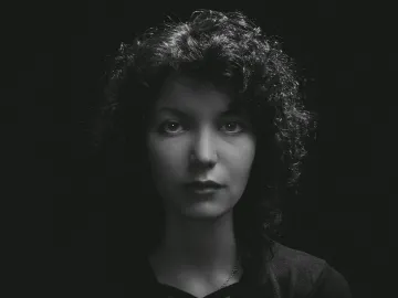 Black and white portrait of a woman with curly hair, highlighting moody and classic tones.