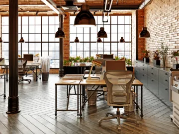 Open plan office with large windows and brick wall