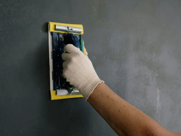 Close-up of a hand smoothing a wall with a spackle