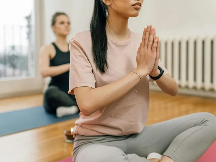 Two women meditate and practice yoga indoors