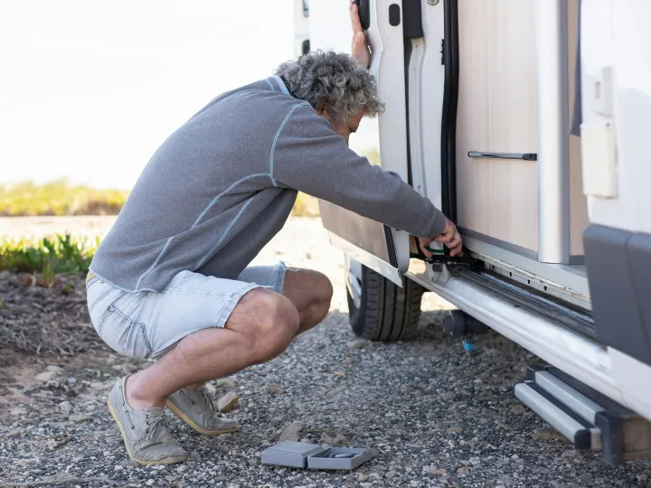 Senior man fixing camper van door mechanism outdoo