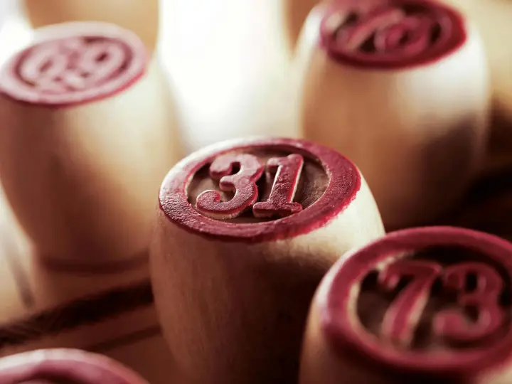 Wooden bingo game chips in focus, displaying numbers 31 and 73.