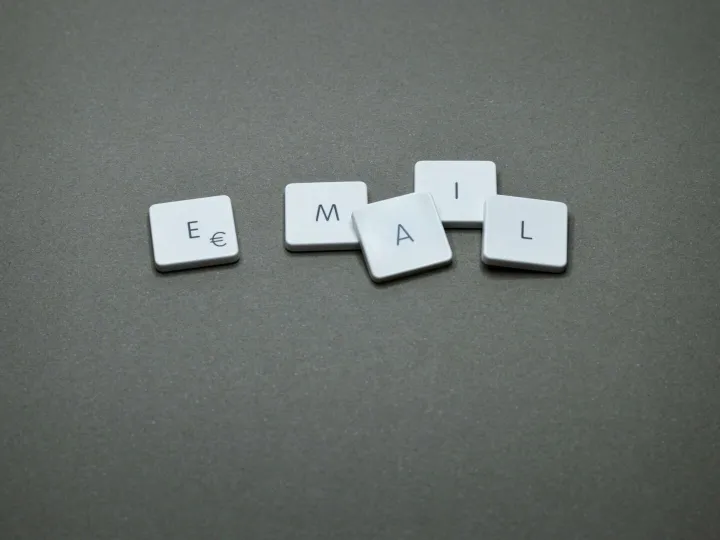 Close-up of the word 'email' formed with letter tiles on a gray surface.