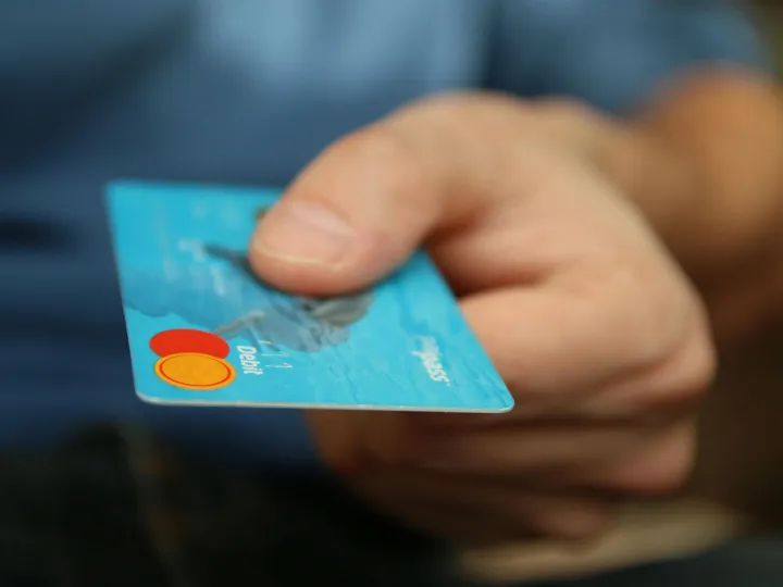 A close-up shot of a hand offering a blue debit