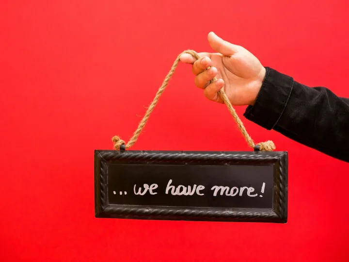 A hand holding a black chalkboard sign with text o