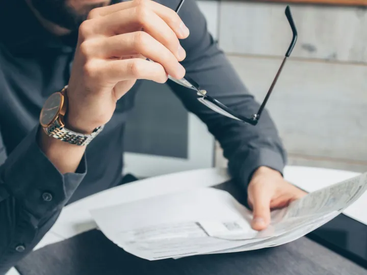 Man in formal attire reviewing paperwork, holding 